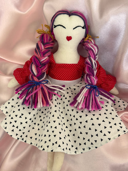 Small plush toy with braided hair and red dress on a white background