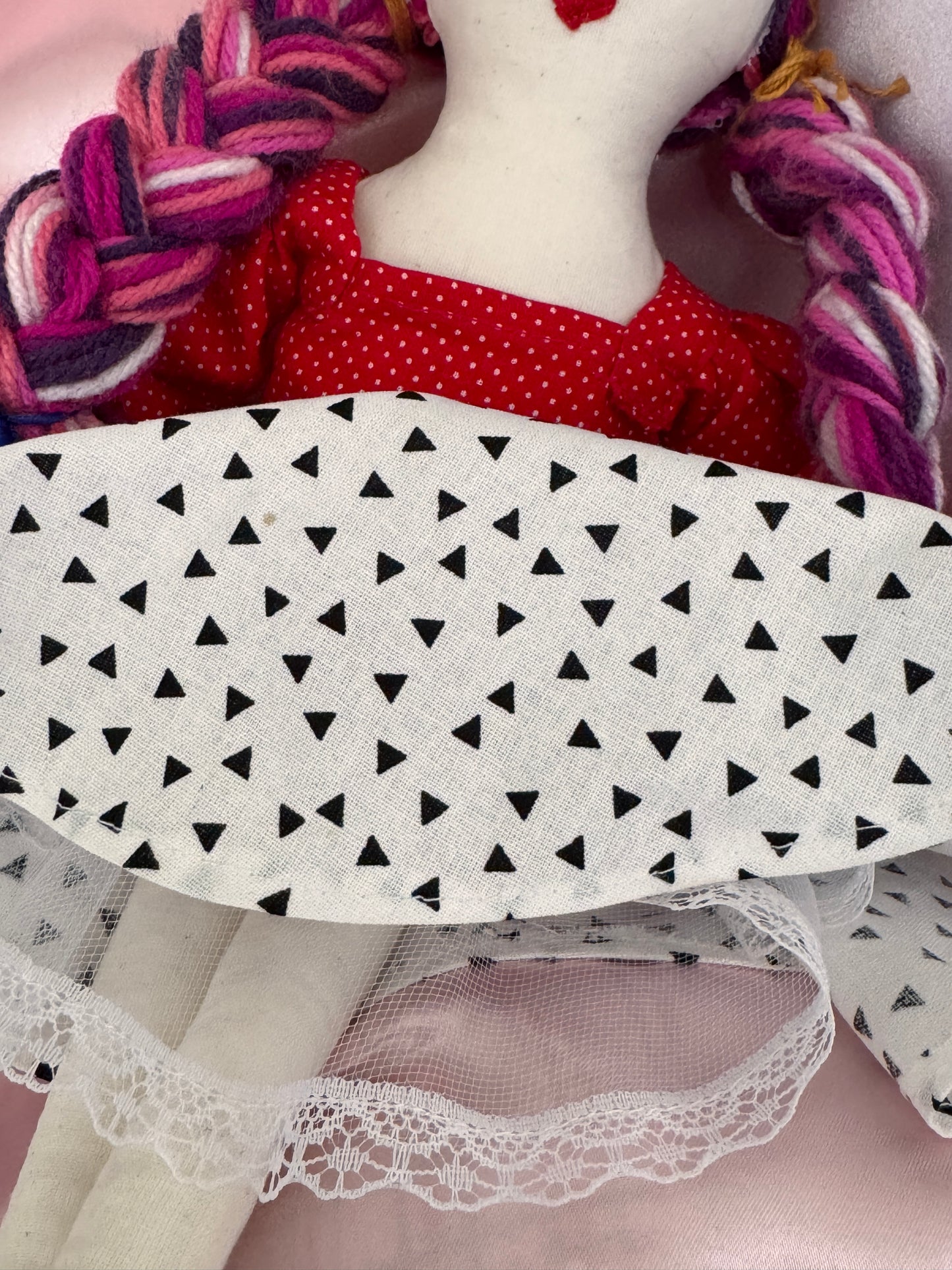 Close-up of various lace and fabric items with a white ironing board cover featuring black triangle pattern.